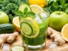 Um copo de suco detox para desinchar verde, refrescante e convidativo, com guarnições de pepino, limão e hortelã, cercado por ingredientes frescos como couve, gengibre e maçãs verdes, evocando saúde e bem-estar.