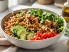 Bowl saudável de grão-de-bico com frango grelhado, folhas verdes, tomate e pepino servido sobre bancada de mármore em cozinha iluminada.
